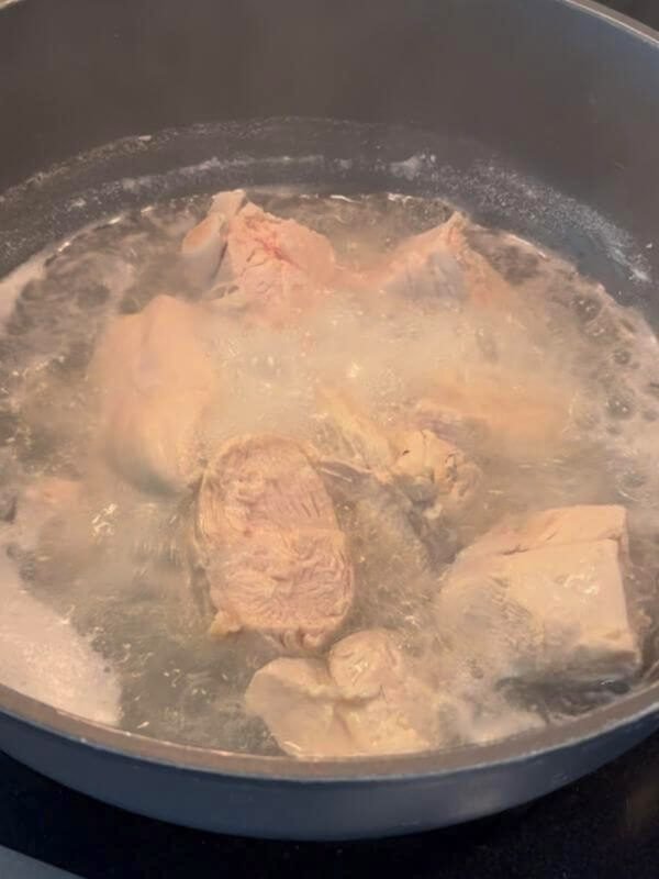 Boiling chicken breast thoroughly in a pot on the stovetop to eliminate bacteria
