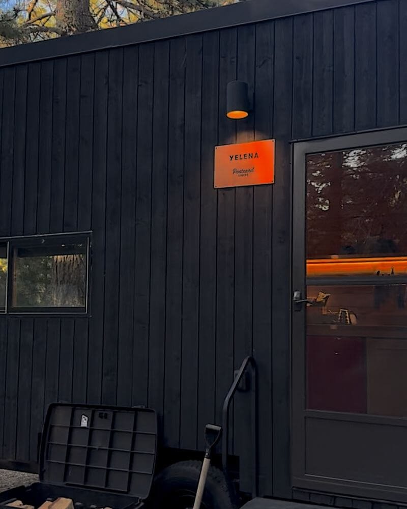 Getaway cabin exterior at dusk with warm glowing lights and firewood box