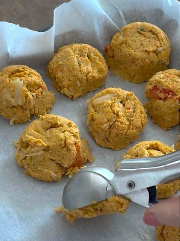 Placing round homemade dog food scoops onto parchment paper on a baking sheet