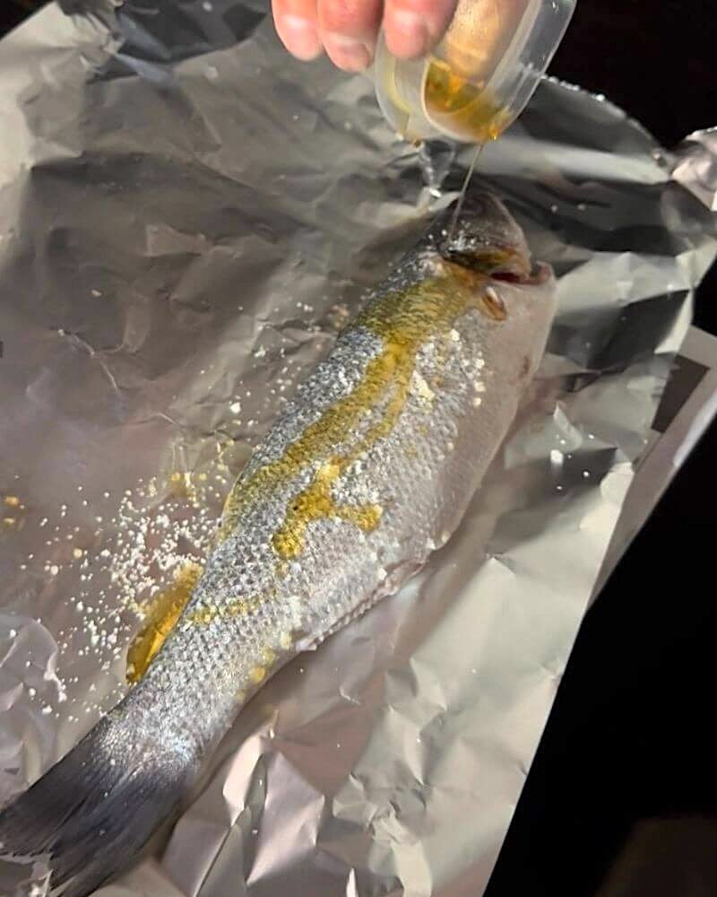 San Clemente Pet Friendly Camping: Our Foil Grill Fail Seasoning whole branzino fish with sesame oil and salt before grilling over campfire