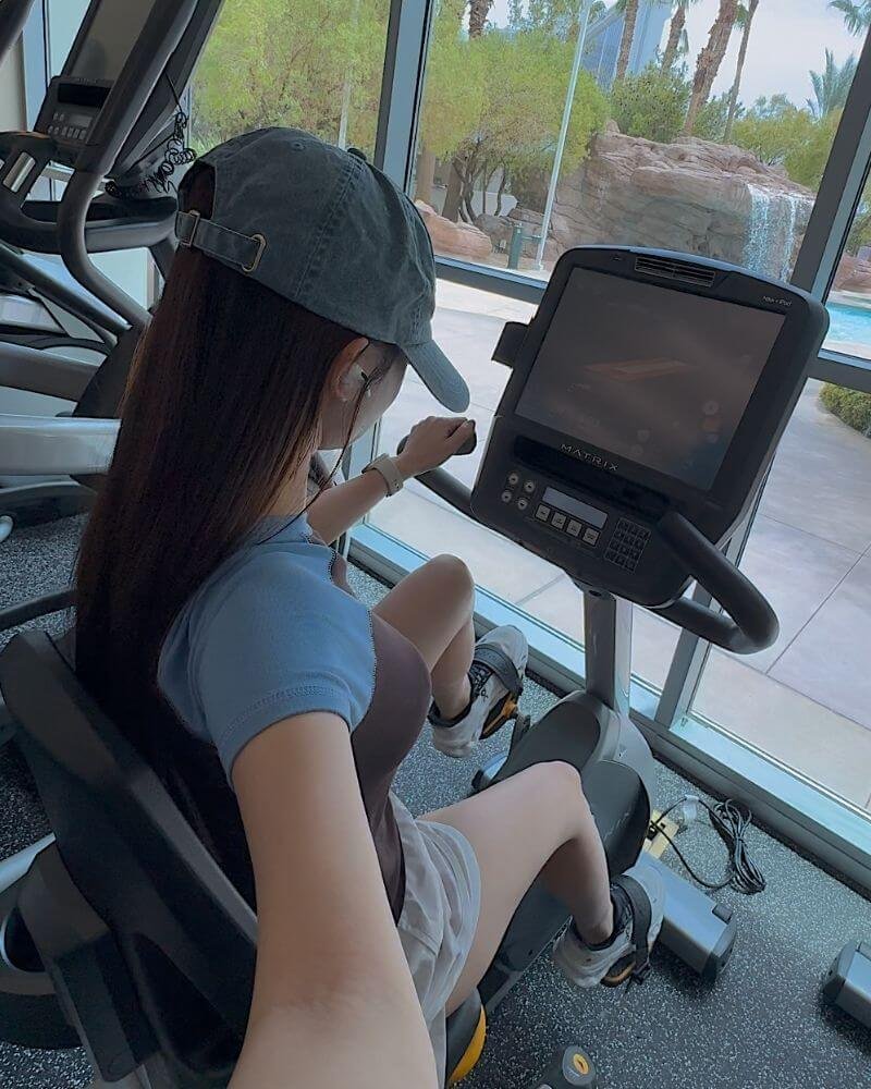 Stationary Bike Zone 2 Workout for Beginners (30-Minute Guide) Woman doing a stationary bike Zone 2 workout for beginners in an indoor fitness space