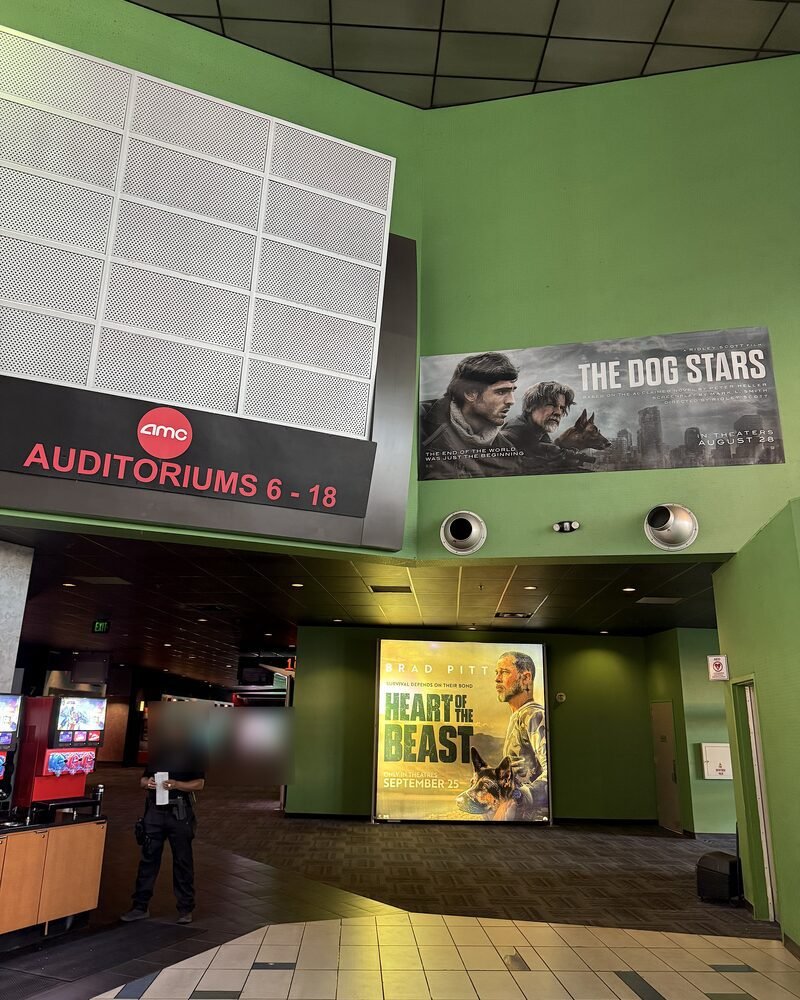 A green movie theater hallway with the Heart of the Beast poster lit up at the far end
