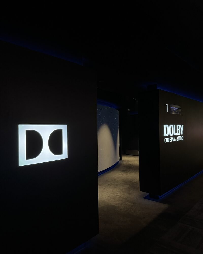 The glowing Dolby Cinema logo at the entrance to a dark movie auditorium