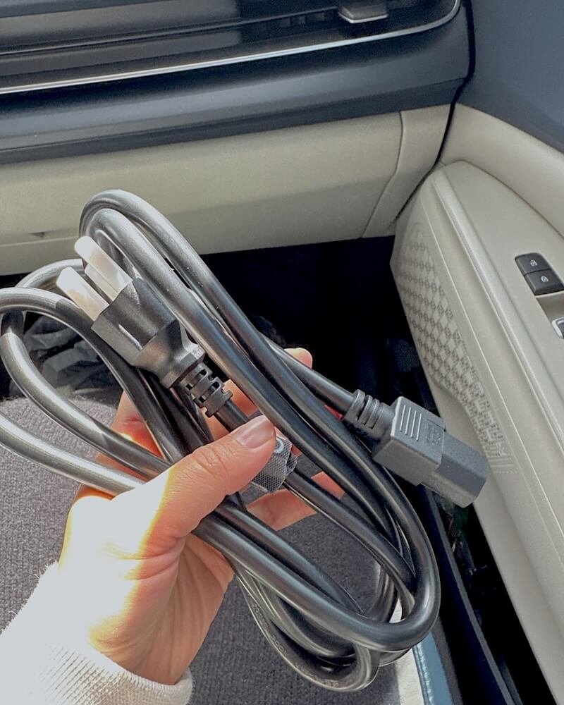 Tent Camping With Dogs: Three Nights With No Power Hand holding a coiled extension cord inside a car before a power station charging run