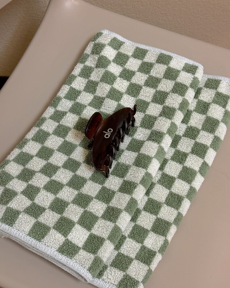 A folded checkered towel from home with a single claw clip resting on top