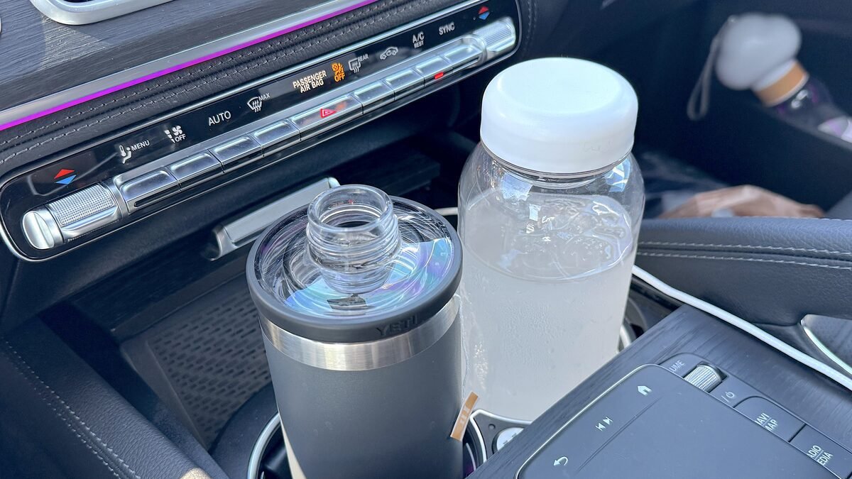 A tumbler and a bottle of electrolyte water in the car cup holder right after a sauna session