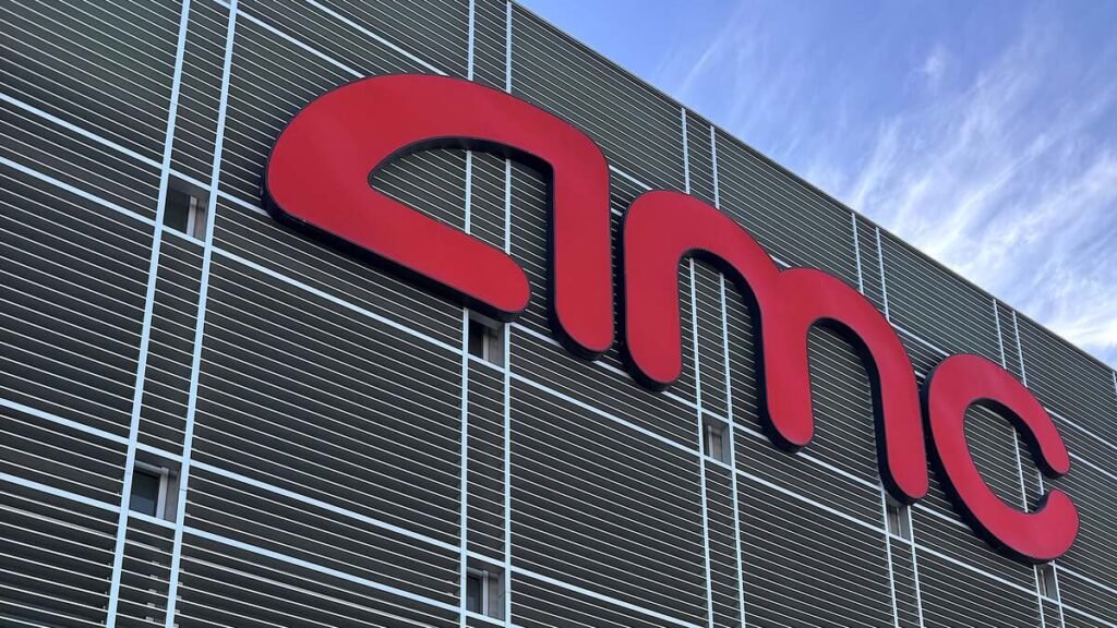 The red AMC logo on the front of a movie theater under a blue sky