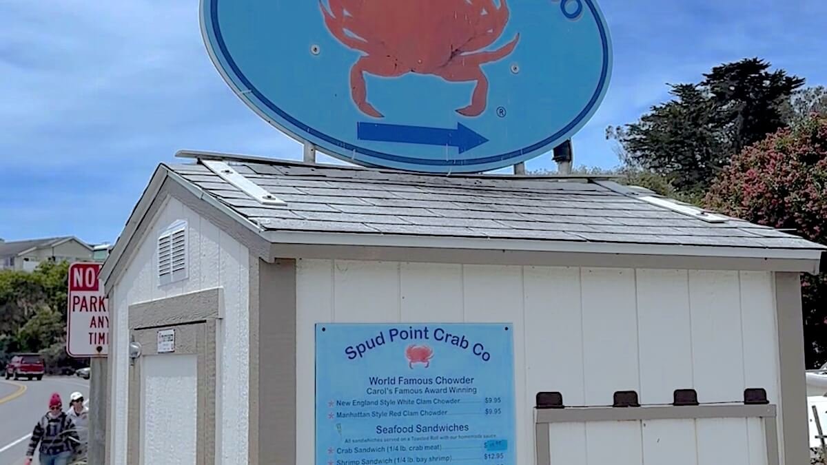 Westside Regional Park Camping With Dogs: What We Wish We'd Known People lined up at the Spud Point Crab Co window with the fish market sign and the Bodega Bay marina behind