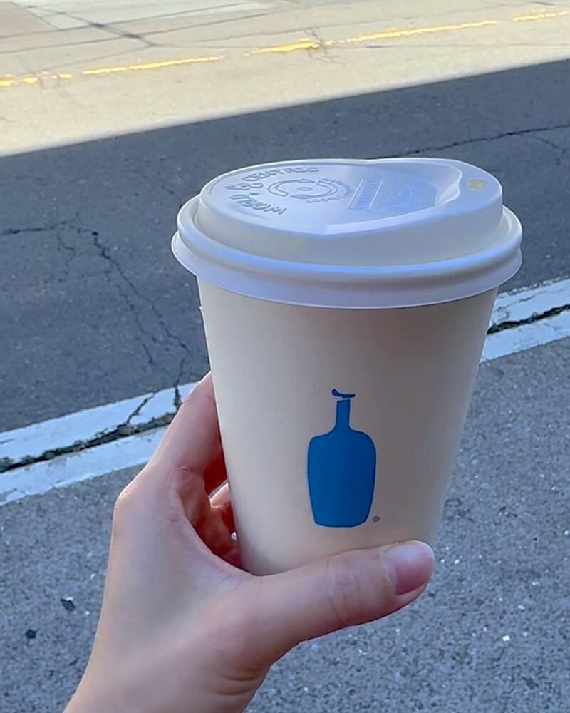 Dog Friendly San Francisco: Two Days With Three Small Dogs Hand holding a takeaway coffee cup on a San Francisco street with parked cars behind
