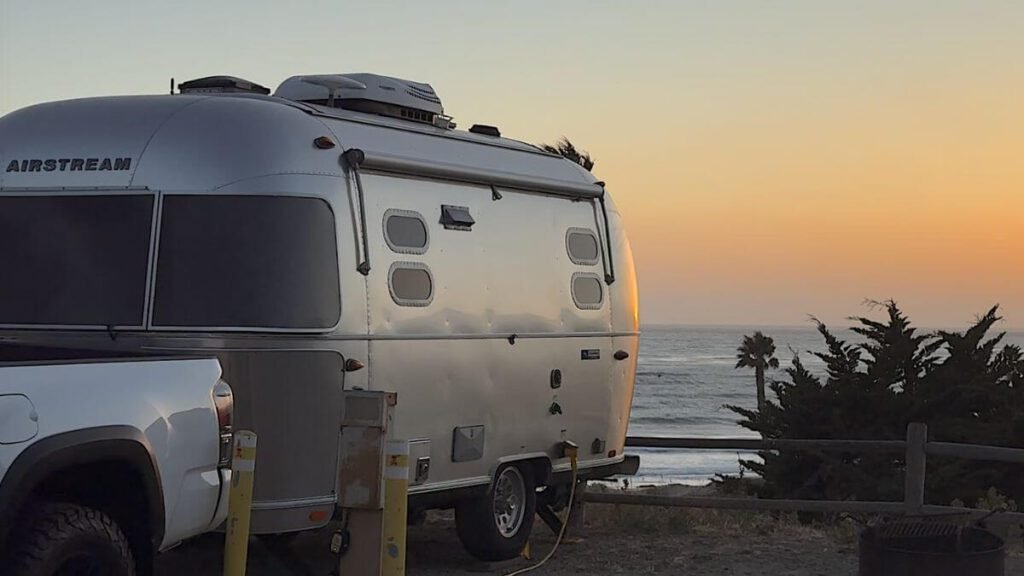 What Is It Like to Camp With No Cell Service? Our Three Days Offline Silver Airstream travel trailer parked at an oceanfront campsite at Jalama Beach during a warm sunset