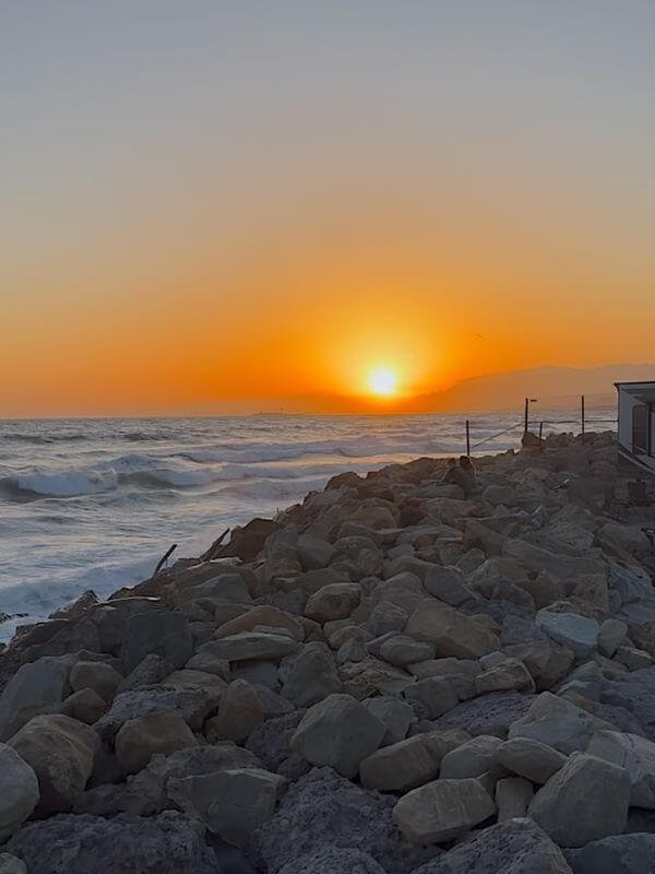 Golden sunset over rocky coastline and ocean waves at Hobson Beach Park