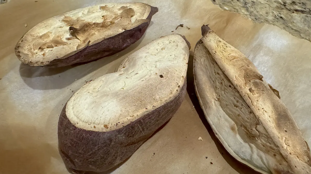How to cook sweet potato for dogs: three plain air fried Korean sweet potatoes cut open and cooling on parchment paper