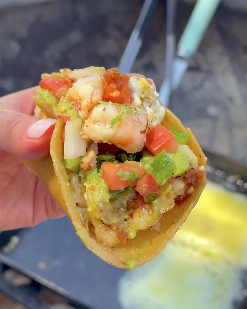 Easy Camping Breakfast: 4 Campfire Griddle Meals We Made (Nothing Prepped at Home) Easy camping breakfast shrimp taco with salsa held over the campfire griddle