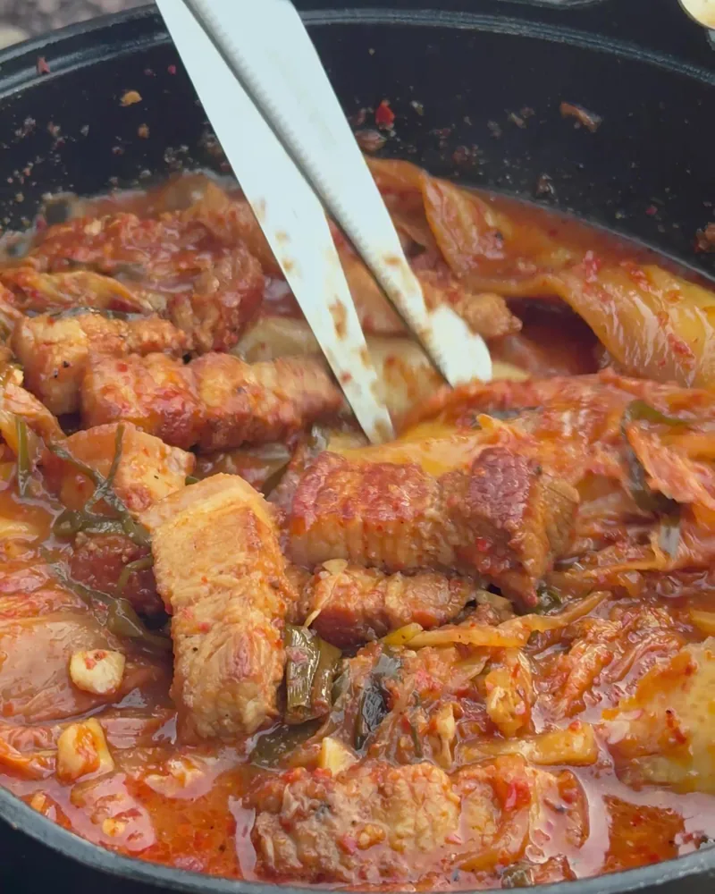 Camping Food List: What We Actually Ate in 3 Nights (Korean Dinners, Drinks, and the Dogs' Food) Camping food list dinner of pork belly kimchi stew simmering in a black pot at camp