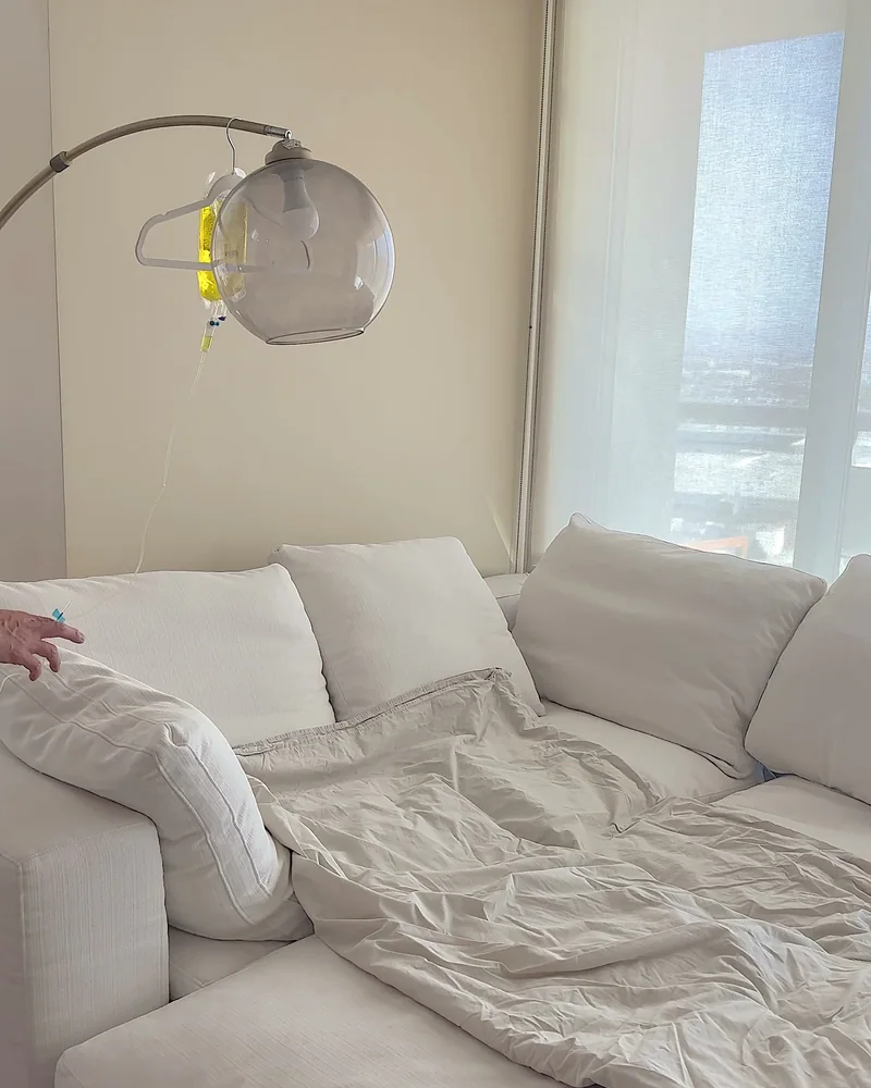 What Is in an IV Drip? Every Ingredient in My At-Home IV Bag (and Why It Turned Yellow) What is in an IV drip: a yellow vitamin IV bag hanging from a floor lamp over a white couch