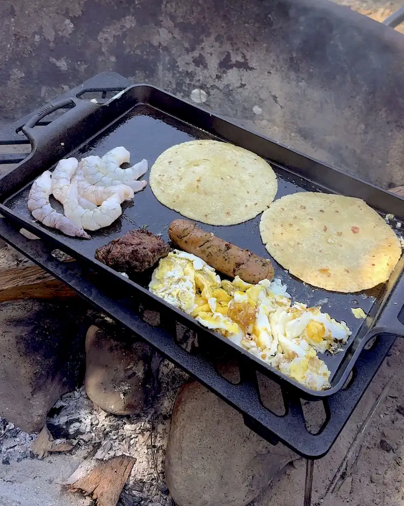 Easy Camping Breakfast: 4 Campfire Griddle Meals We Made (Nothing Prepped at Home) Cast iron griddle on a campfire grate with shrimp, corn tortillas, sausage and scrambled eggs