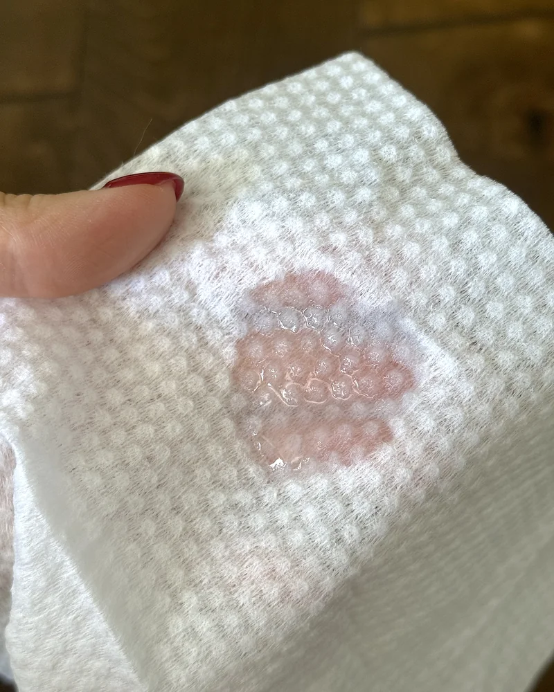 A few drops of clear ear cleaner soaked into a white textured wipe