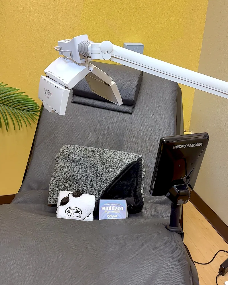 Hydromassage Bed: My Honest Review After 10+ Sessions (and the Exact Settings I Use) Gray massage bed with a folded towel and a face light panel on an arm in a small private room