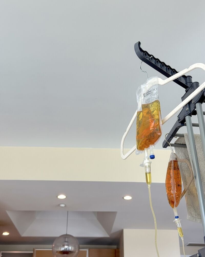 How Long Does an IV Drip Take? My 90-Minute vs 6-Hour Drips Two IV bags hanging side by side from clothes hangers on a drying rack, one for me and one for my husband