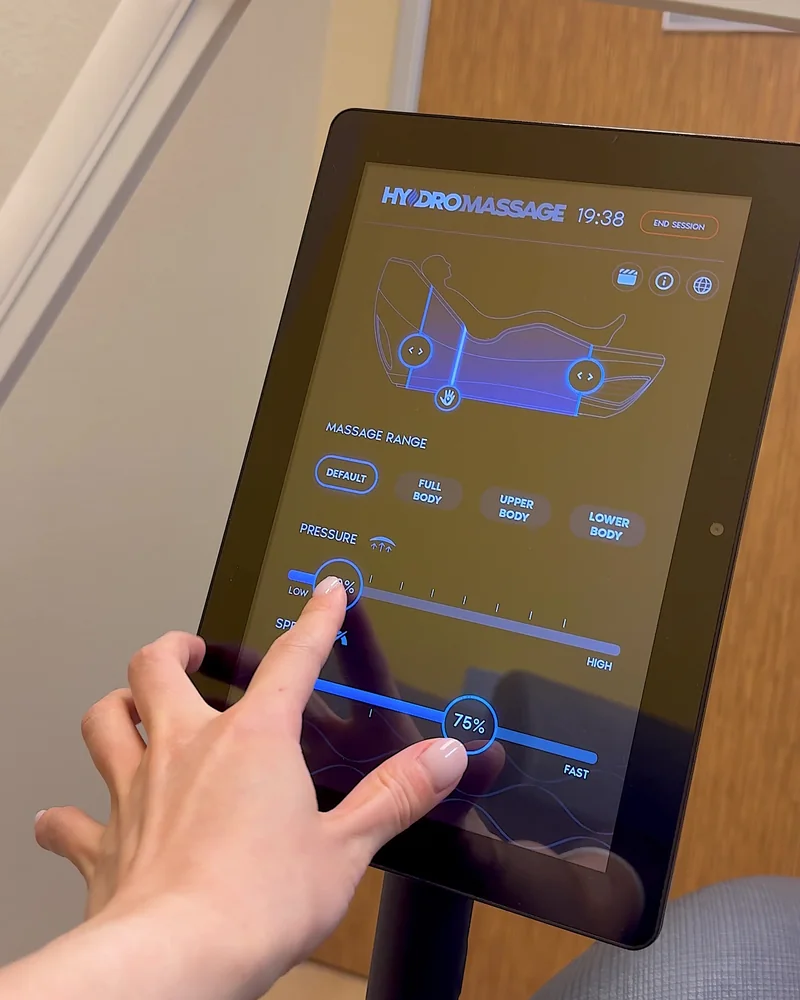Hydromassage Bed: My Honest Review After 10+ Sessions (and the Exact Settings I Use) Hand adjusting hydromassage settings on a touchscreen tablet