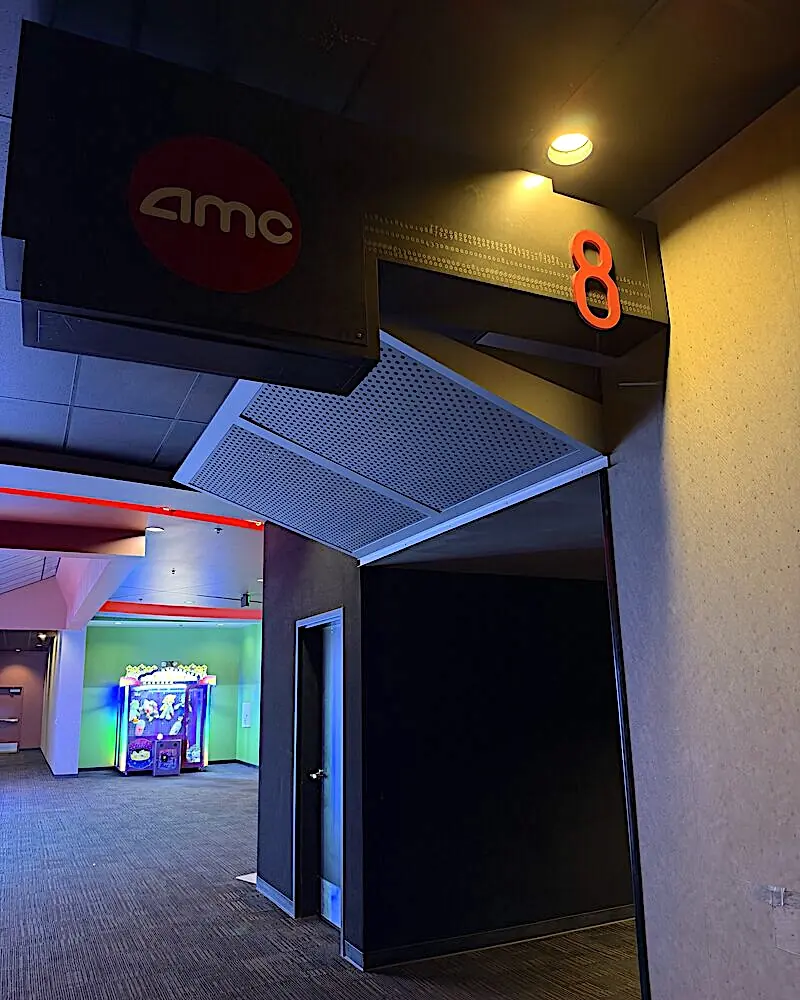 AMC auditorium entrance with a red AMC logo sign and an orange number 8 above a dark hallway