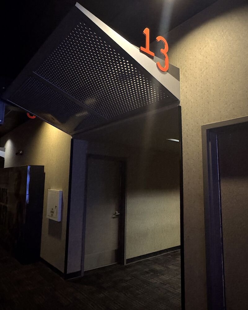 I Almost Skipped The Nightmare Before Christmas 3D. One Scene Changed My Mind Dimly lit movie theater auditorium entrance with an orange number sign above the door