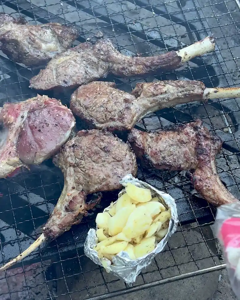 Cooking on a Fire Pit at Camp (6 Things We Made, From Lamb Chops to Pork Belly) Browned lamb chops on the grate next to an open foil pouch of roasted garlic cloves