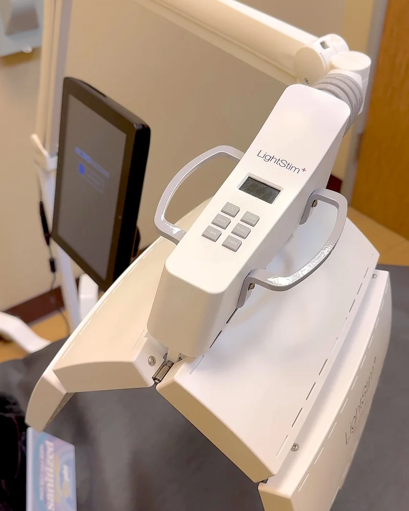 Tanning Salon Red Light Therapy: My Honest Routine After 10+ Face Sessions LightStim LED face panel handle with a small screen and control buttons