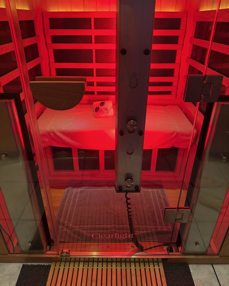 Infrared Sauna Cost: My $69.99 Membership vs Buying One (With Red Light) Looking into the infrared booth through the glass door with the red light panel glowing