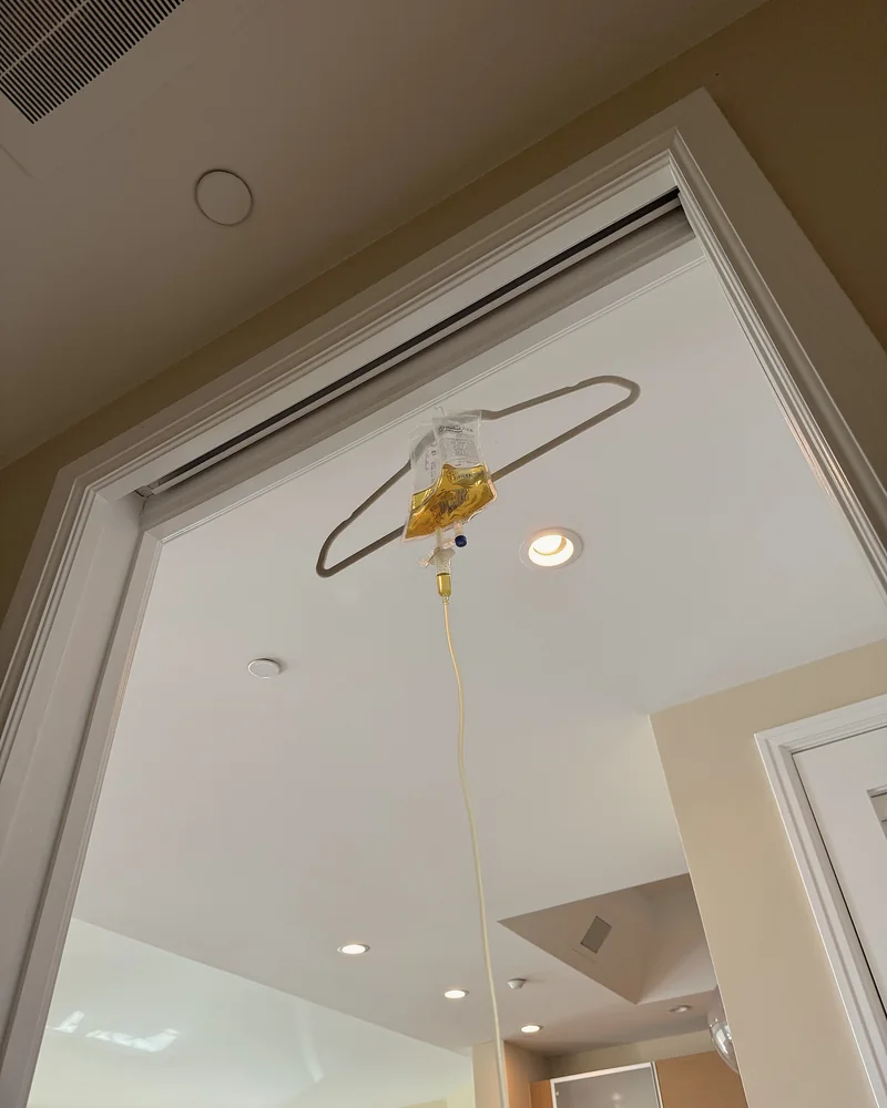 What Is in an IV Drip? Every Ingredient in My At-Home IV Bag (and Why It Turned Yellow) IV bag hanging from a hanger in a doorway with the tube running down