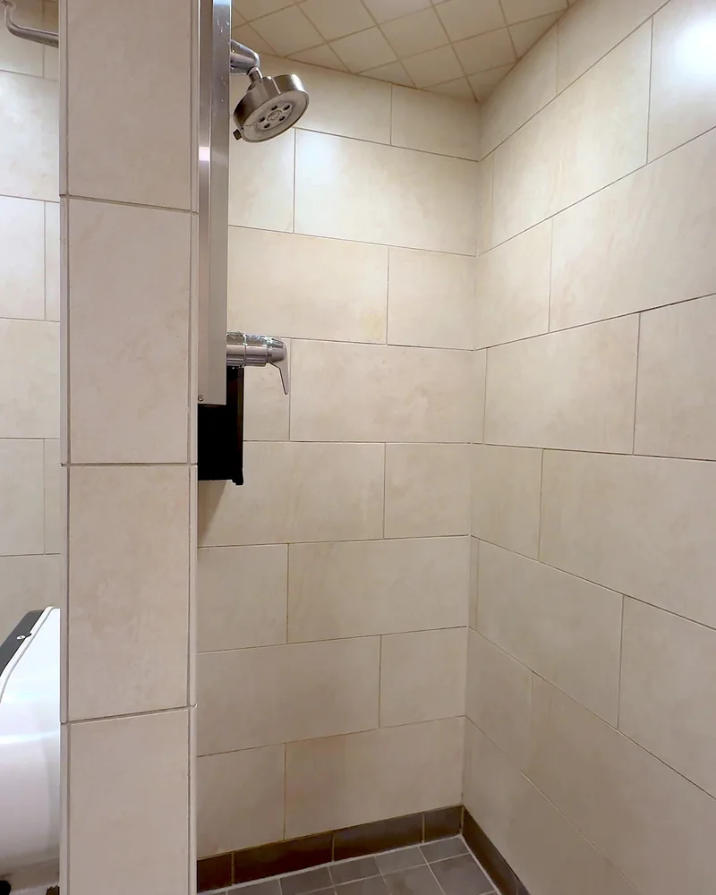 Truck Stop Showers: What Our First Pilot Shower Was Really Like (and What It Cost) Clean tiled shower stall with a wall mounted shower head