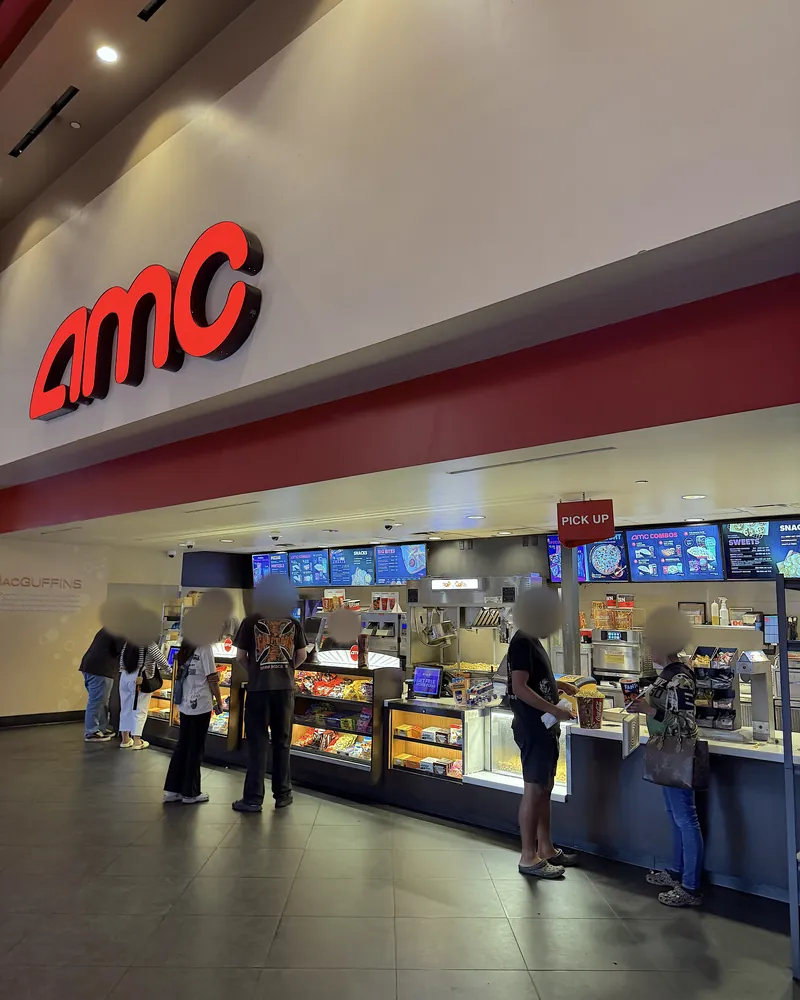 Is The Social Reckoning Worth Seeing? My 7.5/10 Review (No Spoilers) AMC concession stand with the red AMC sign and menu screens above the counter