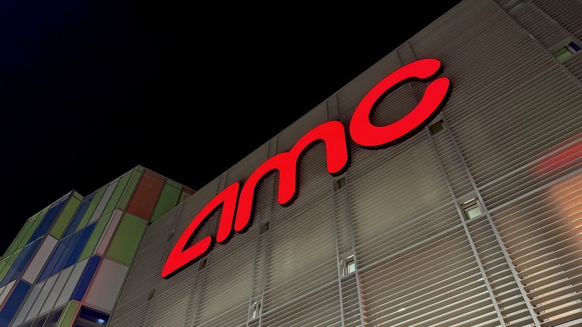 Red AMC sign glowing on the outside of the theater at night