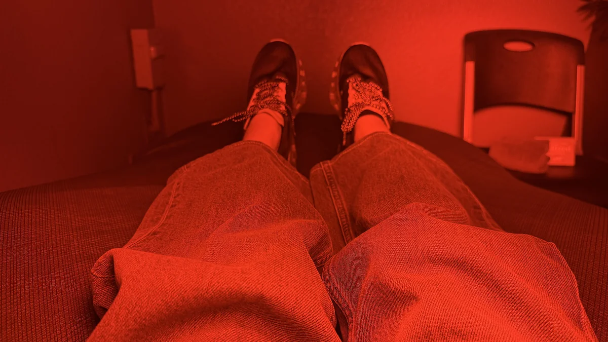 Hydromassage Bed: My Honest Review After 10+ Sessions (and the Exact Settings I Use) Legs in pants and sneakers resting on a hydromassage bed under red light