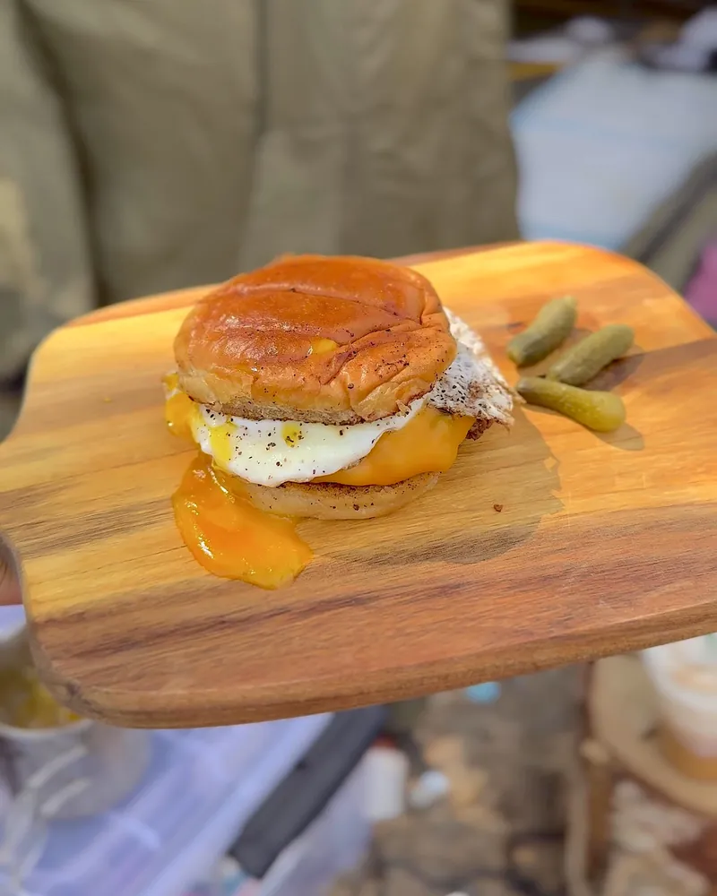 Easy Camping Breakfast: 4 Campfire Griddle Meals We Made (Nothing Prepped at Home) Breakfast burger with a runny fried egg and mini pickles on a wooden board