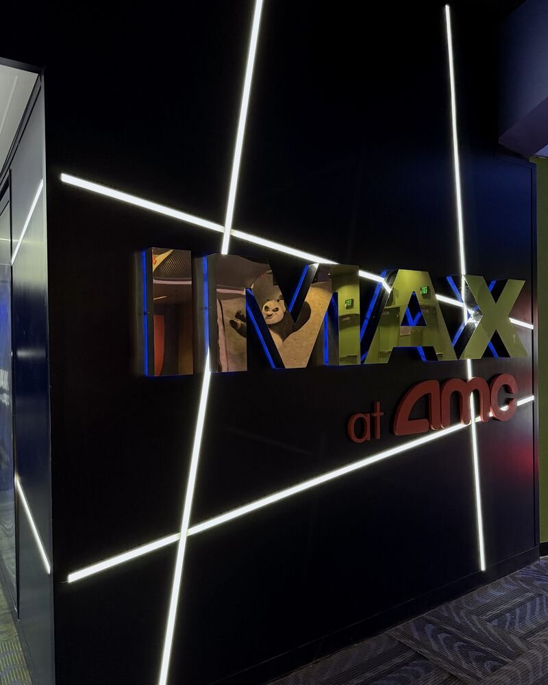 Large IMAX at AMC letters on a black wall crossed by white light strips