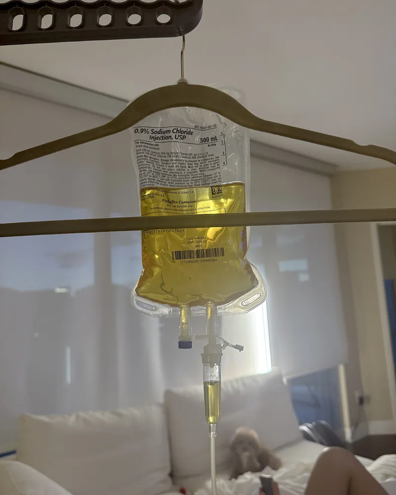 NAD IV Therapy: What My First 1,000 mg Drip Was Like (And the Week After) A yellow 500 mL IV bag on a clothes hanger with the couch and a resting dog in the background
