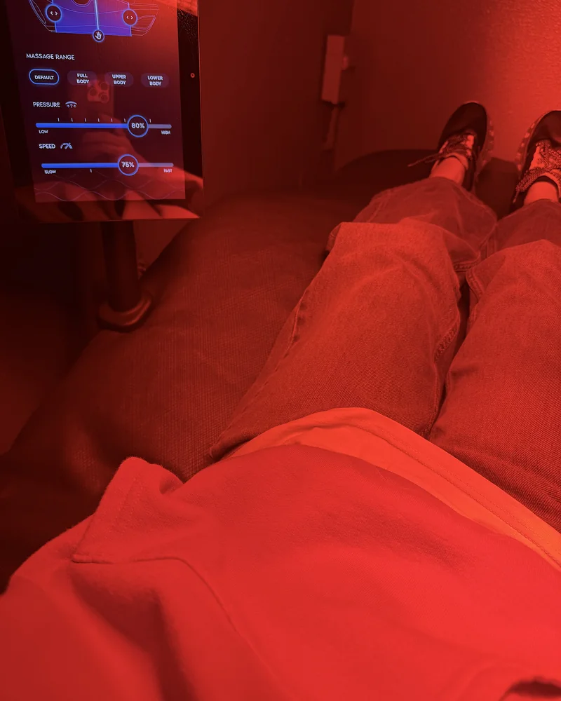 Hydromassage Bed: My Honest Review After 10+ Sessions (and the Exact Settings I Use) Legs stretched out on a massage bed under red light with the control tablet nearby