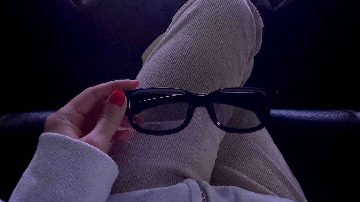 I Almost Skipped The Nightmare Before Christmas 3D. One Scene Changed My Mind Black 3D glasses held up in a dark theater with purple light
