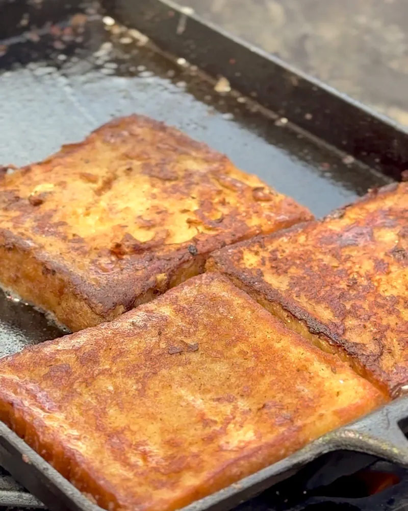 Easy Camping Breakfast: 4 Campfire Griddle Meals We Made (Nothing Prepped at Home) Golden brown French toast slices cooking on a cast iron griddle
