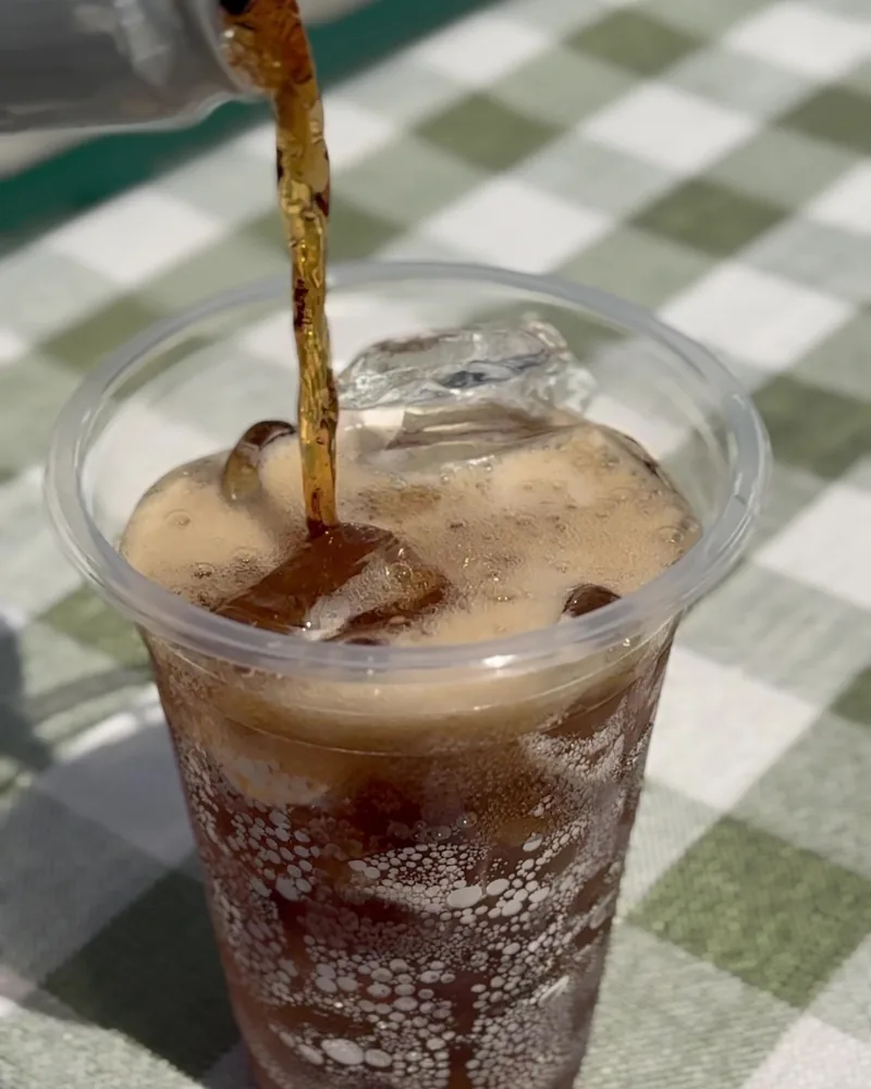 Camping Food List: What We Actually Ate in 3 Nights (Korean Dinners, Drinks, and the Dogs' Food) Zero sugar cola being poured over ice into a plastic cup at a camp table