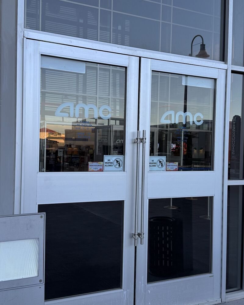 Glass front doors of an AMC movie theater with the AMC logo on each door