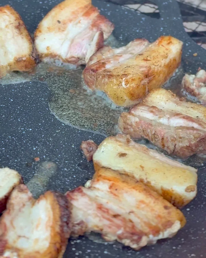 Cooking on a Fire Pit at Camp (6 Things We Made, From Lamb Chops to Pork Belly) Bite-size pieces of pork belly crisping up on a cast iron griddle over the fire